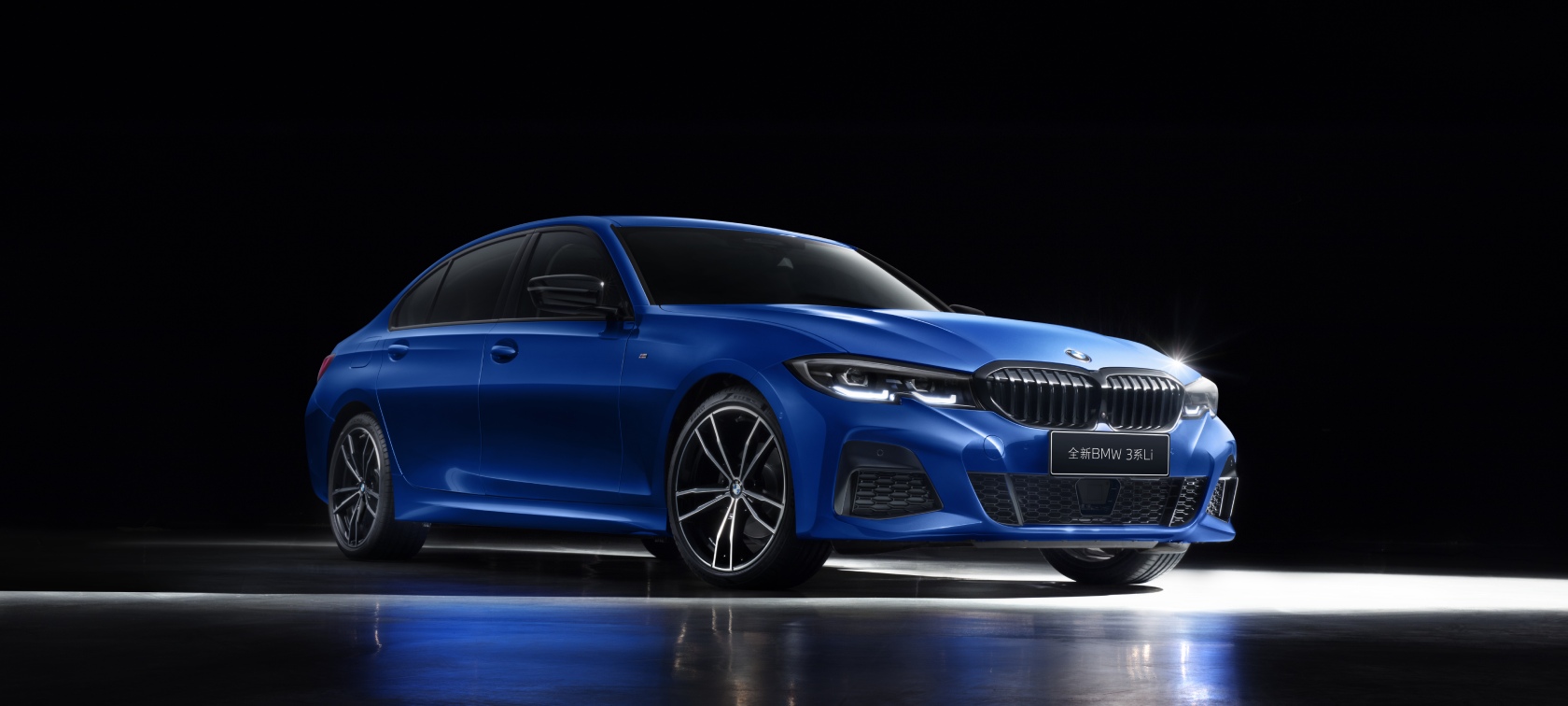 运动豪华,本色过人 Three-quarter side shot of the BMW 3 Series Sedan on asphalt in front of an urban backround with passengers.