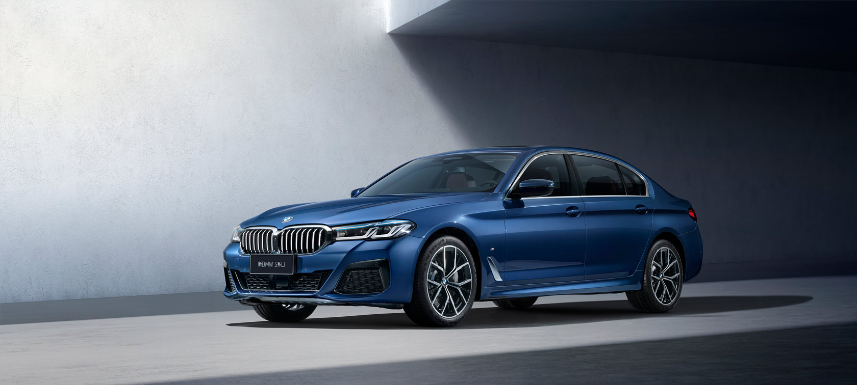 运动豪华,本色过人 Three-quarter side shot of the BMW 3 Series Sedan on asphalt in front of an urban backround with passengers.