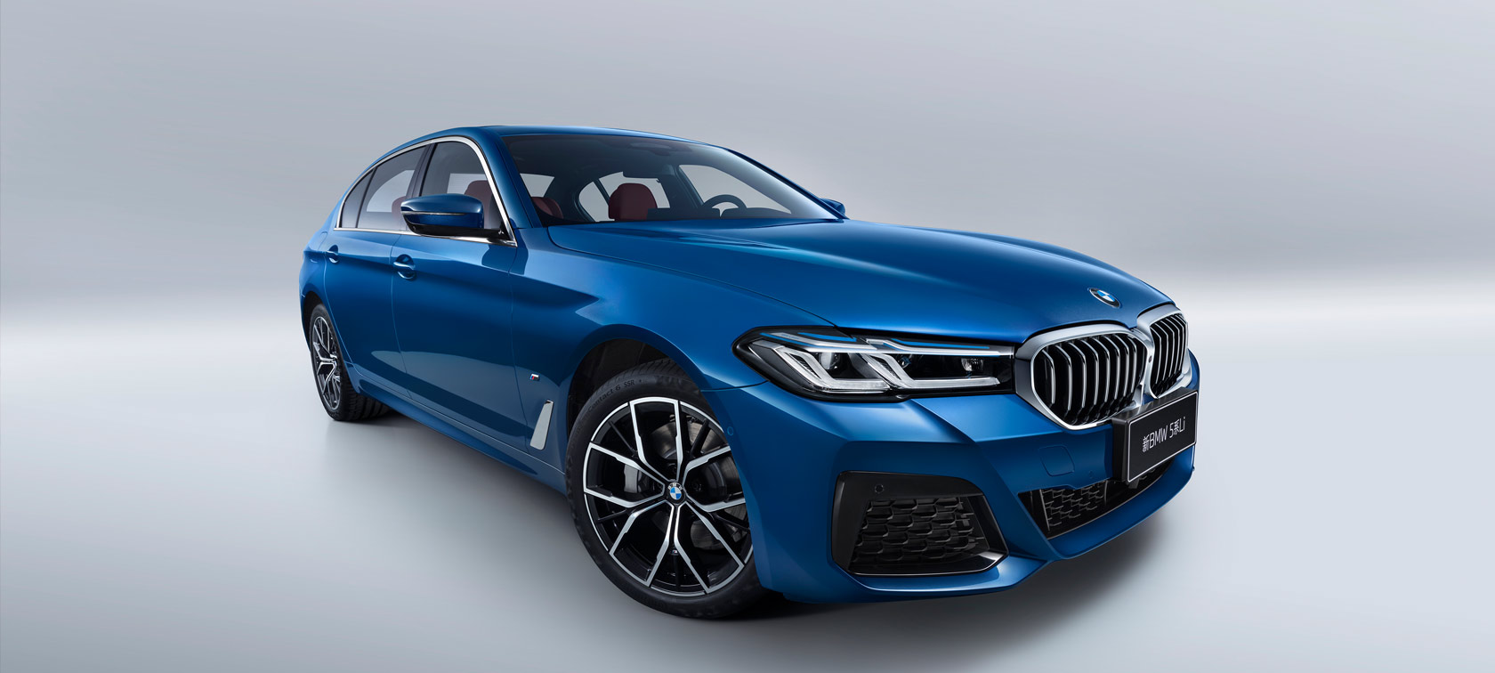 运动豪华,本色过人 Three-quarter side shot of the BMW 3 Series Sedan on asphalt in front of an urban backround with passengers.