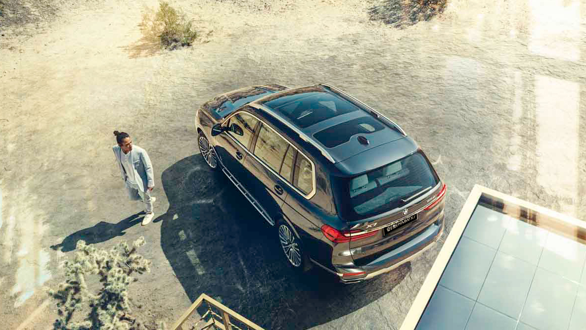 Adaptive 2-Axle Air Suspension BMW X7 driving in side perspective in front of rural background
