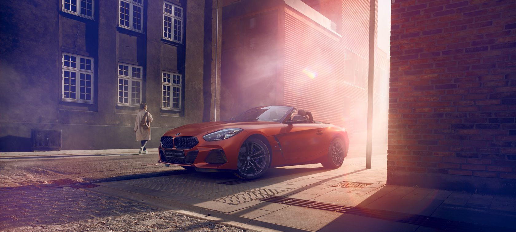 全新BMWZ4敞篷跑车银霜限量版 Three-quarter side shot of the BMW 3 Series Sedan on asphalt in front of an urban backround with passengers.